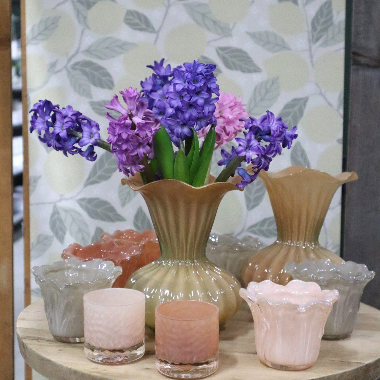 Lila och rosa hyacinter arrangerade i en beige vas.